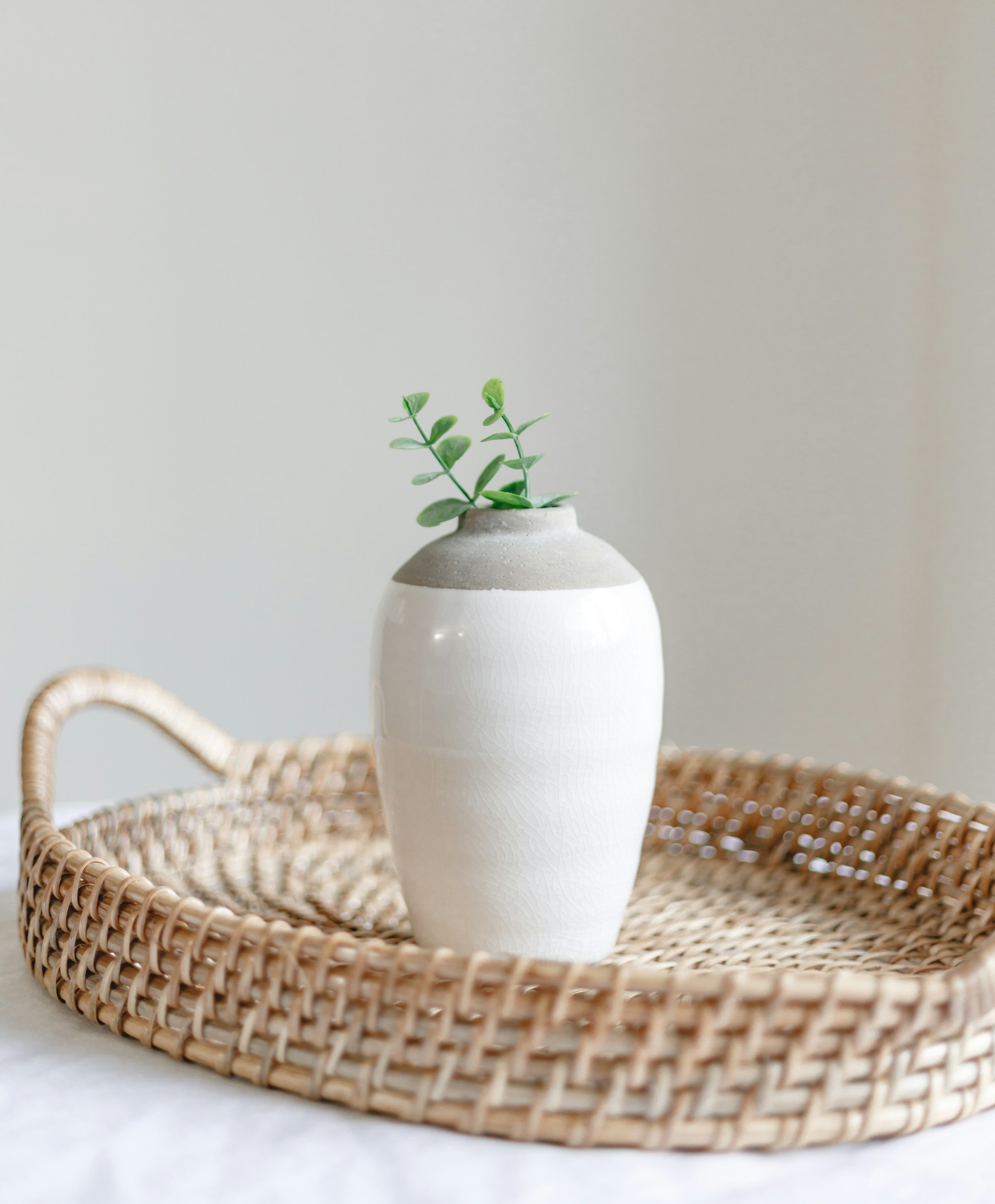 Vase de céramique blanche posé sur un plateau en rotin, coin déco du salon d'accueil